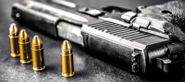 Close-up image of a semi-automatic handgun and four bullets placed on a dark surface. This image reflects the practical focus of Copperhead Outlaws LLC's courses on responsible gun handling and usage.